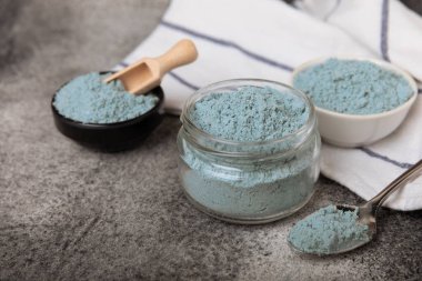 Blue spirulina powder in bowls and spoon on black marble background. Natural vegan superfood. food supplement. place for text. Copy space.