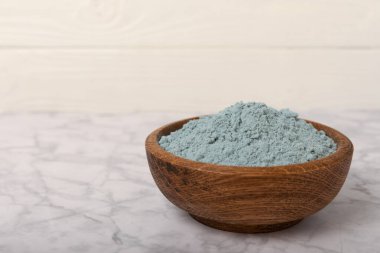 Blue spirulina powder in a bowl on a white marble background. Natural vegan superfood. food supplement. place for text. Copy space.
