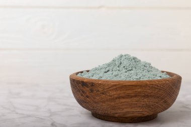 Blue spirulina powder in a bowl on a white marble background. Natural vegan superfood. food supplement. place for text. Copy space.