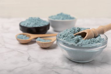 Blue spirulina powder in bowls and spoon on white marble background. Natural vegan superfood. food supplement. place for text. Copy space.