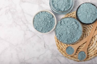 Blue spirulina powder in bowls and spoon on white marble background. Natural vegan superfood. food supplement. place for text. Copy space.