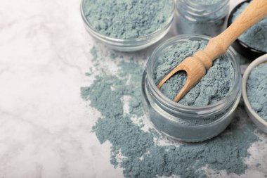 Blue spirulina powder in bowls and spoon on white marble background. Natural vegan superfood. food supplement. place for text. Copy space.