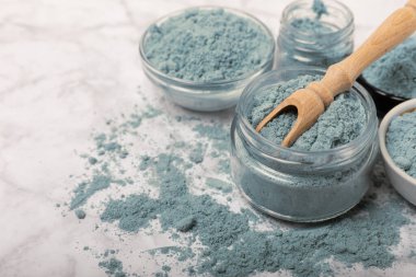 Blue spirulina powder in bowls and spoon on white marble background. Natural vegan superfood. food supplement. place for text. Copy space.
