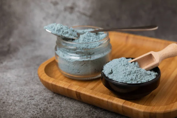 Blue spirulina powder in bowls and spoon on black marble background. Natural vegan superfood. food supplement. place for text. Copy space.