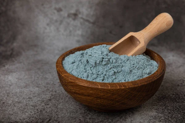 Blue spirulina powder in bowls and spoon on black marble background. Natural vegan superfood. food supplement. place for text. Copy space.