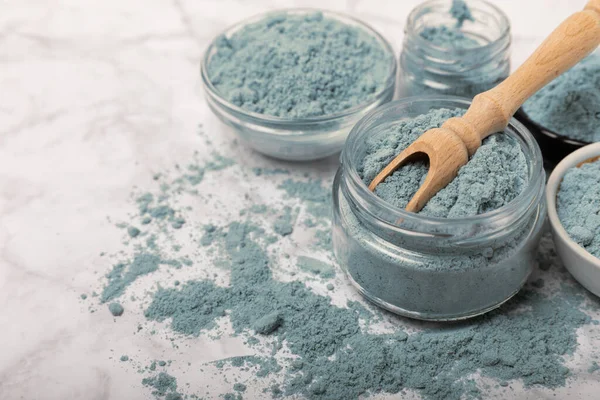 Blue spirulina powder in bowls and spoon on white marble background. Natural vegan superfood. food supplement. place for text. Copy space.