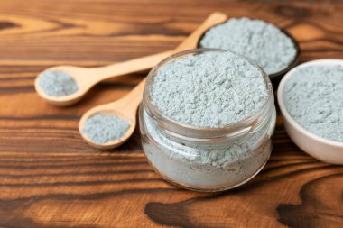 Blue spirulina powder in bowls and spoon on brown texture background. Natural vegan superfood. food supplement. place for text. Copy space.