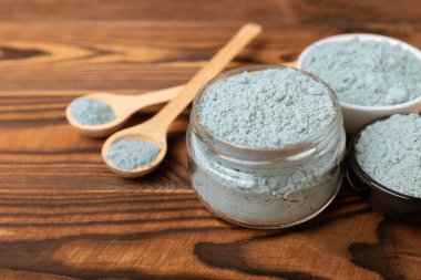 Blue spirulina powder in bowls and spoon on brown texture background. Natural vegan superfood. food supplement. place for text. Copy space.
