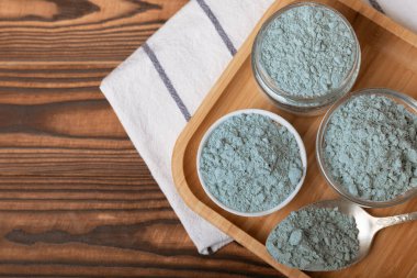 Blue spirulina powder in bowls and spoon on brown texture background. Natural vegan superfood. food supplement. place for text. Copy space.