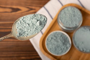 Blue spirulina powder in bowls and spoon on brown texture background. Natural vegan superfood. food supplement. place for text. Copy space.