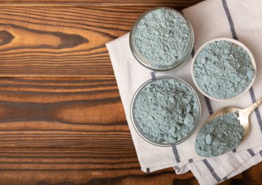 Blue spirulina powder in bowls and spoon on brown texture background. Natural vegan superfood. food supplement. place for text. Copy space.