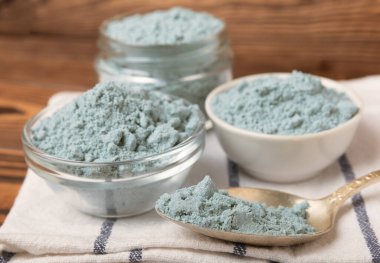 Blue spirulina powder in bowls and spoon on brown texture background. Natural vegan superfood. food supplement. place for text. Copy space.