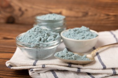 Blue spirulina powder in bowls and spoon on brown texture background. Natural vegan superfood. food supplement. place for text. Copy space.