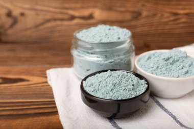 Blue spirulina powder in bowls and spoon on brown texture background. Natural vegan superfood. food supplement. place for text. Copy space.