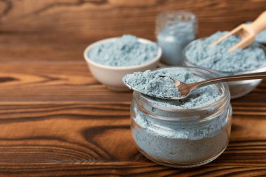 Blue spirulina powder in bowls and spoon on brown texture background. Natural vegan superfood. food supplement. place for text. Copy space.