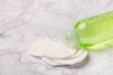 Micellar cleansing water and pads for removing makeup and cleansing the skin of sebium on a white marble table.Beauty concept. Flat lay.Copy the space text. Place to copy.