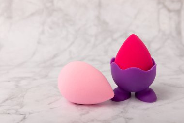 Beauty blender on light marble background. Cosmetics, makeup application tool. Beauty concept. Copy space. Place for text.