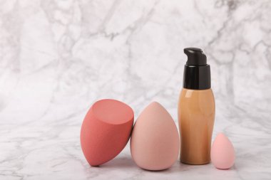 Makeup artist tools on marble texture table. Beauty blender, sponge, concealer and foundation. Beauty concept. Place for text.Copy space.