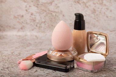 Makeup artist's tools on a brown marble dressing table. Beauty blender, sponge, brushes for powder, blush, concealer, foundation and eye shadow. Beauty concept. Place for text.Copy space.
