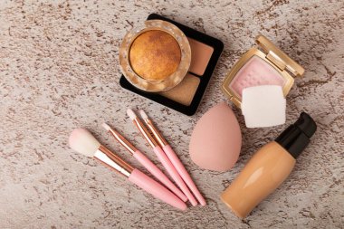 Makeup artist's tools on a brown marble dressing table. Beauty blender, sponge, brushes for powder, blush, concealer, foundation and eye shadow. Beauty concept. Place for text.Copy space.