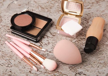 Makeup artist's tools on a brown marble dressing table. Beauty blender, sponge, brushes for powder, blush, concealer, foundation and eye shadow. Beauty concept. Place for text.Copy space.