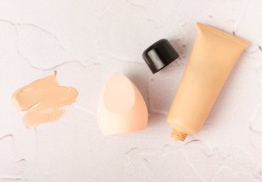 Makeup artist tools on marble texture table. Beauty blender, sponge, concealer and foundation. Beauty concept. Place for text.Copy space.