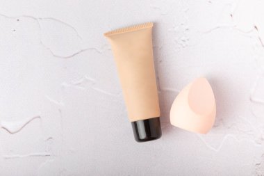 Makeup artist tools on marble texture table. Beauty blender, sponge, concealer and foundation. Beauty concept. Place for text.Copy space.