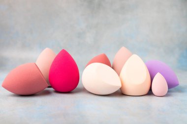 Beauty blender on a blue marble background. Cosmetics, makeup application tool. Beauty concept. Copy space. Place for text.