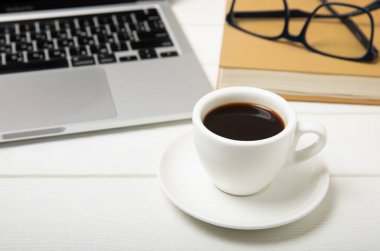 Work desk with laptop, blank notepad, coffee cup, eyeglasses and pen on textured wooden table. Flat lay, side view. copy spce.Place for text.