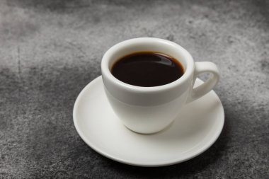 A cup of aromatic coffee on a black marble table. Hot refreshing espresso. Morning drink. Cheerful morning concept.