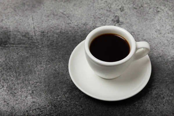 A cup of aromatic coffee on a black marble table. Hot refreshing espresso. Morning drink. Cheerful morning concept.