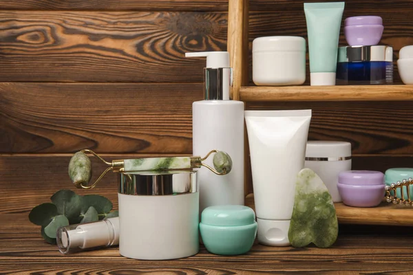 Care cosmetics for face, body and hair on a wooden shelf. A set of cosmetic products shampoo, cream, serum and scrub on a shelf in the bathroom. Foreground. copy space. Beauty concept.