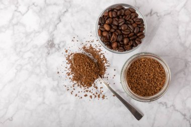 Coffee granules and coffee beans on a white marble background. Instant coffee drink. Energy hot drink. Place for text. Place for copy. Cheerful morning concept.