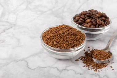 Coffee granules and coffee beans on a white marble background. Instant coffee drink. Energy hot drink. Place for text. Place for copy. Cheerful morning concept.