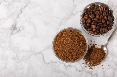 Coffee granules and coffee beans on a white marble background. Instant coffee drink. Energy hot drink. Place for text. Place for copy. Cheerful morning concept.
