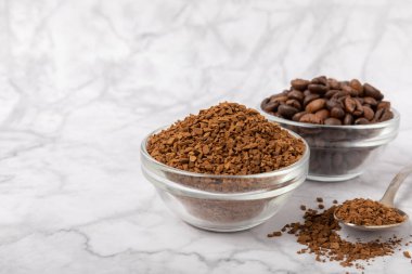 Coffee granules and coffee beans on a white marble background. Instant coffee drink. Energy hot drink. Place for text. Place for copy. Cheerful morning concept.