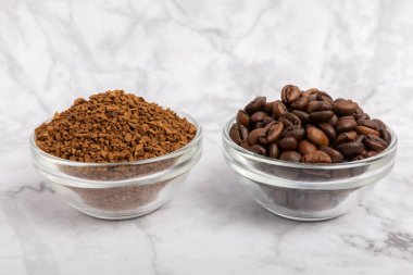 Coffee granules and coffee beans on a white marble background. Instant coffee drink. Energy hot drink. Place for text. Place for copy. Cheerful morning concept.