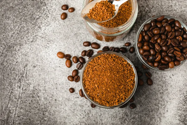 Coffee granules and coffee beans on a black textured background. Instant coffee drink. Energy hot drink. Place for text. Place for copy. Cheerful morning concept.