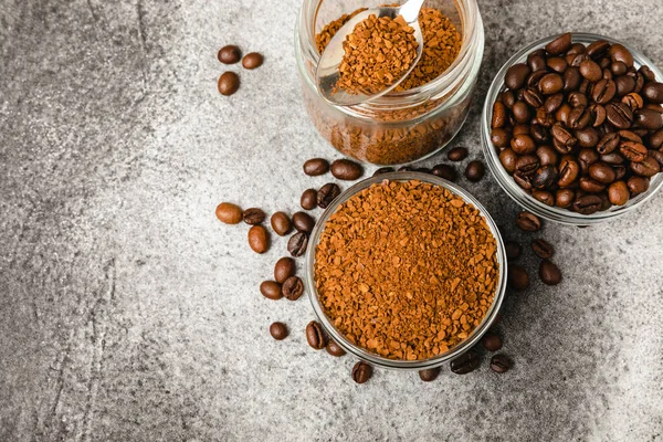 Coffee granules and coffee beans on a black textured background. Instant coffee drink. Energy hot drink. Place for text. Place for copy. Cheerful morning concept.