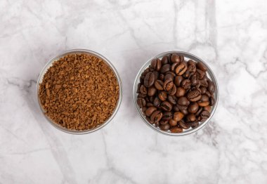 Coffee granules and coffee beans on a white marble background. Instant coffee drink. Energy hot drink. Place for text. Place for copy. Cheerful morning concept.