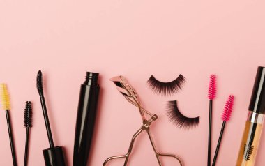 Composition with eyelash brush, eyelash curler, mascara and false eyelashes on pink background. Flat lay composition. Beauty industry concept.Place for text. Copy Spys.