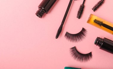 Composition with eyelash brush, eyelash curler, mascara and false eyelashes on pink background. Flat lay composition. Beauty industry concept.Place for text. Copy Spys.