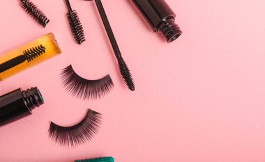 Composition with eyelash brush, eyelash curler, mascara and false eyelashes on pink background. Flat lay composition. Beauty industry concept.Place for text. Copy Spys.
