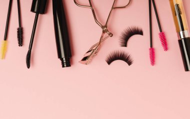 Composition with eyelash brush, eyelash curler, mascara and false eyelashes on pink background. Flat lay composition. Beauty industry concept.Place for text. Copy Spys.