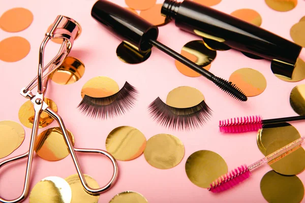 Composition with eyelash brush, eyelash curler, mascara and false eyelashes on pink background. Flat lay composition. Beauty industry concept.Place for text. Copy Spys.