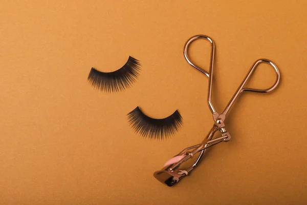 Composition with eyelash curler and false eyelashes on a colored background. Flat lay composition. Beauty industry concept.Place for text. Copy Spys.