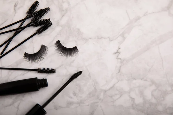 Composition with mascara and eyelash brushes, false eyelashes on a textured background. Flat lay composition. Beauty industry concept.Place for text. Copy Spys.