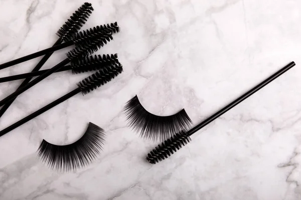 Composition with mascara and eyelash brushes, false eyelashes on a textured background. Flat lay composition. Beauty industry concept.Place for text. Copy Spys.