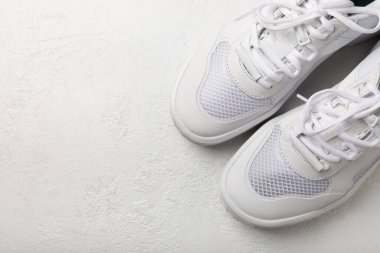 Pair of white shoes on a white texture background. Sport shoes. Unisex. Street style.
