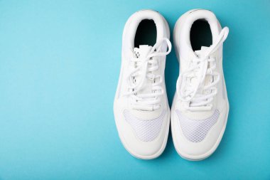 Pair of white shoes on a blue paper background. Sport shoes. Unisex. Street style.